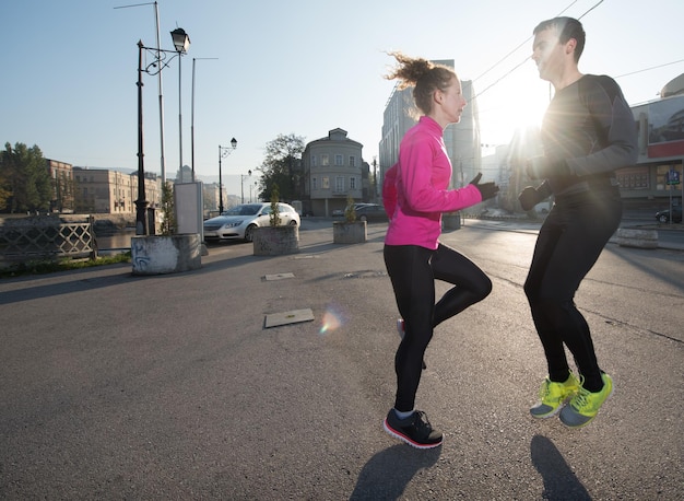 Joggendes Paar, das sich vor dem morgendlichen Laufen in der Stadt aufwärmt und dehnt