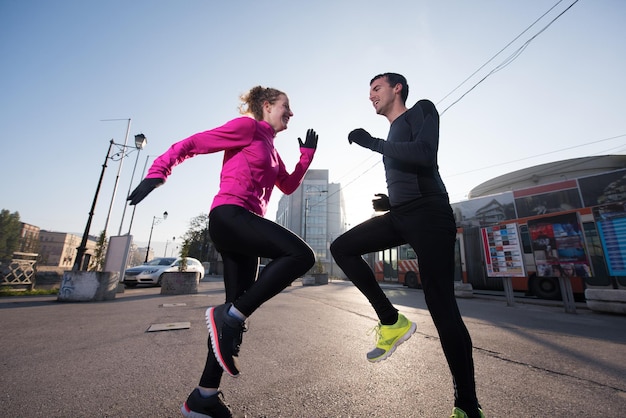 Joggendes Paar, das sich vor dem morgendlichen Laufen in der Stadt aufwärmt und dehnt