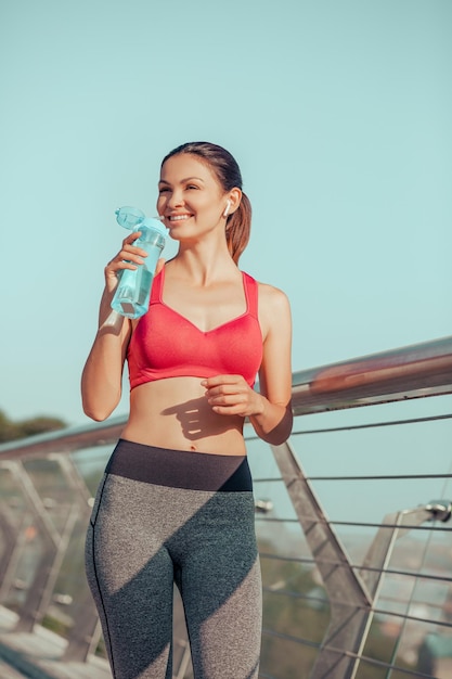 Foto jogger femle después de hacer ejercicio bebiendo agua al aire libre