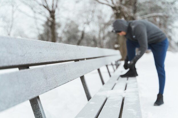 Jogger man se ata los zapatos durante su entrenamiento de invierno en un parque de la ciudad