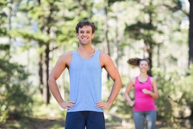 Jogger de pie con mujer en segundo plano.