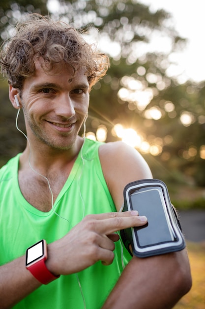 Jogger sonriente escuchando música desde el teléfono móvil