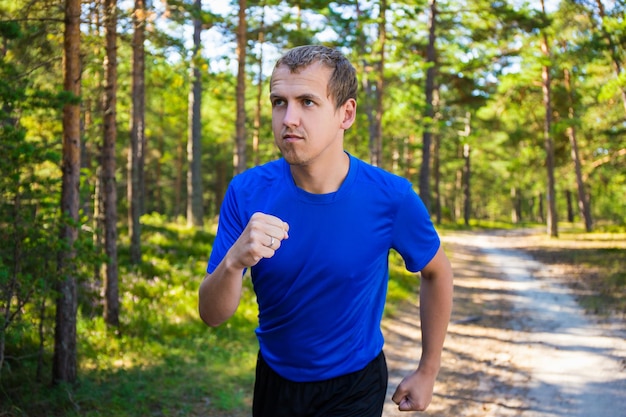 Jogging joven guapo corriendo en el bosque de verano