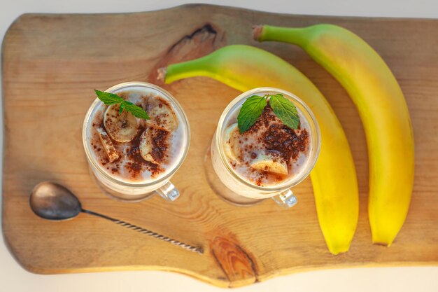 Joghurt-Gelee-Dessert mit Bananen-Erdbeer-Kakao, frischer Minze in einem Glas auf einem Holzbrett. Gesunde vegane Süßspeisen