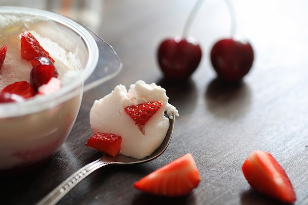 Joghurt mit frischen saftigen Erdbeeren und Kirschen auf einem Holztisch