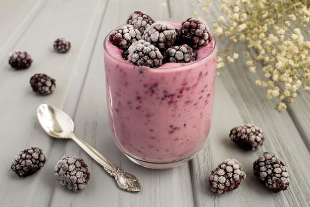 Joghurt mit gefrorenen Brombeeren auf dem grauen Holz