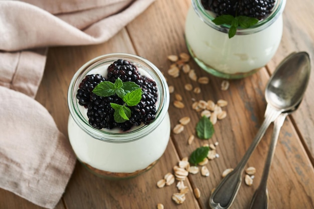 Joghurt mit Müsli, Brombeerbeeren und Müsli, serviert im Glasgefäß auf Holzhintergrund Gesundes Frühstückskonzept Gesundes Essen zum Frühstück von oben