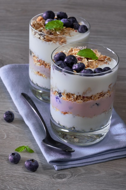 Joghurt mit Müsli und Blaubeeren mit Minze, gesunder Nachtisch auf Holz