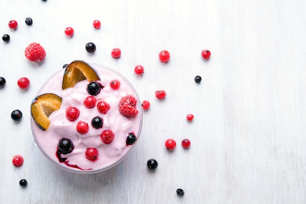 Joghurt mit Obst, Pflaumen, Beeren auf einem weißen Tisch. Energiefrühstück für den Morgen