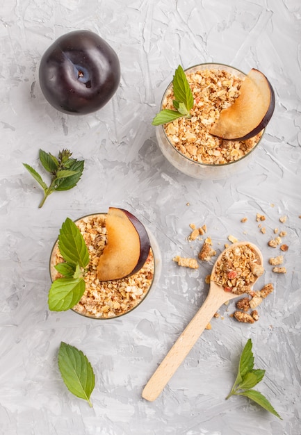 Joghurt mit Pflaumen, Chiasamen und Müsli in einem Glas und Holzlöffel