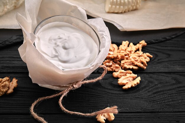 Joghurt oder Sauerrahm in rustikaler Schüssel auf Holzhintergrund, Ansicht von oben.