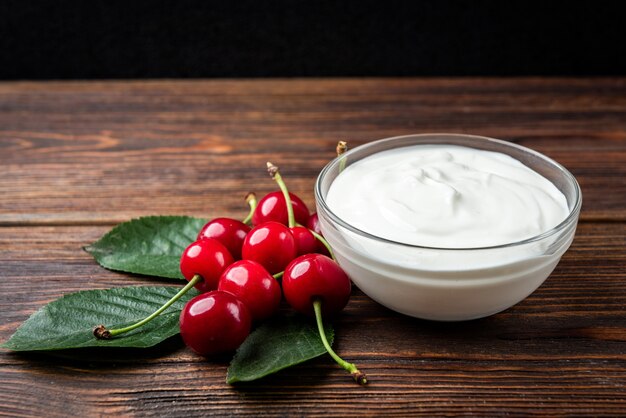 Joghurt und Kirsche auf dunklem Holz.