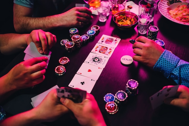 Jogo de cartas de poker e fichas na mesa com as mãos dos jogadores