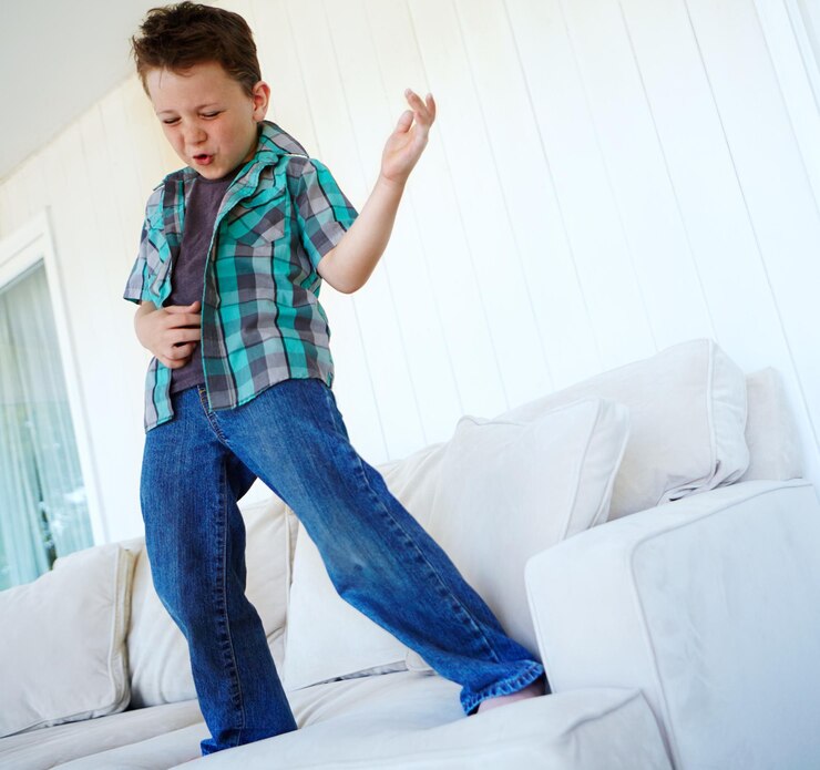 Foto jogo de dança ou menino com guitarra de ar no sofá para humor de comédia ou piada engraçada para rock and roll criança feliz excitada ou criança louca com celebração de música ou instrumento imaginário no sofá em casa