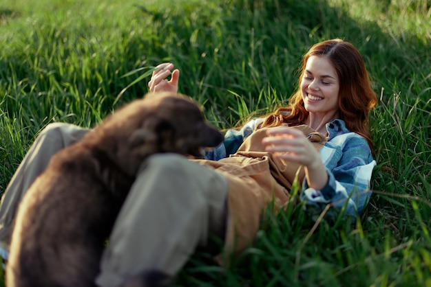 Jogo de mulher com seu cachorro na natureza sorrindo e deitado na grama verde no parque feliz relacionamento saudável entre amante e animal de estimação Foto de alta qualidade