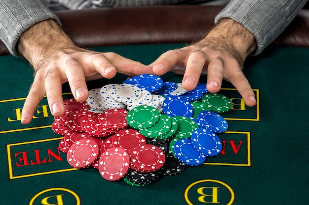 Foto jogo de pôquer. fichas na mesa verde. fichas em mãos masculinas