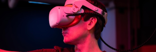 Jogo de realidade virtual e jogador de realidade virtual divertido jogando no jogo de filmagem de simulação futurista em óculos 3d e joysticks na sala de entretenimento vr com tecnologia de inovação e banner de luz neon