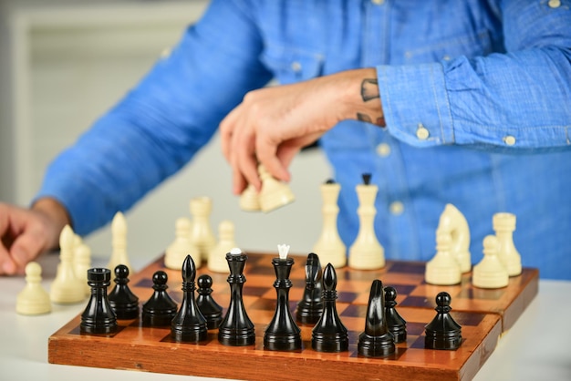 Jogo de sucesso da competição homem concentrado desenvolvendo estratégia de xadrez  jogando jogo de tabuleiro com amigo movendo peça durante torneio de xadrez  movendo peças no tabuleiro de xadrez homem segura peça