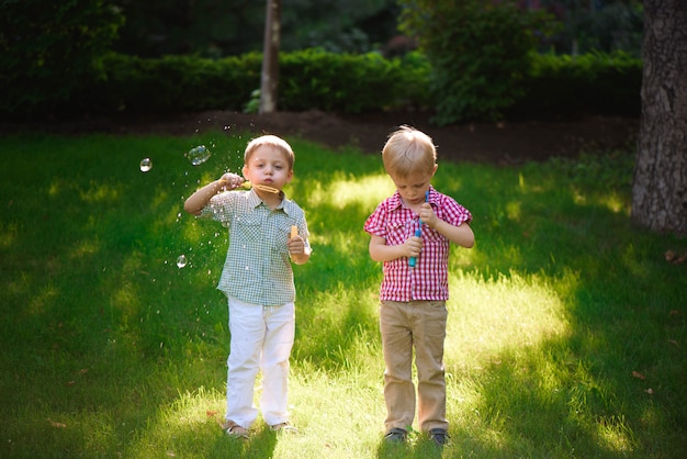 Jogo feliz de dois meninos nas bolhas ao ar livre