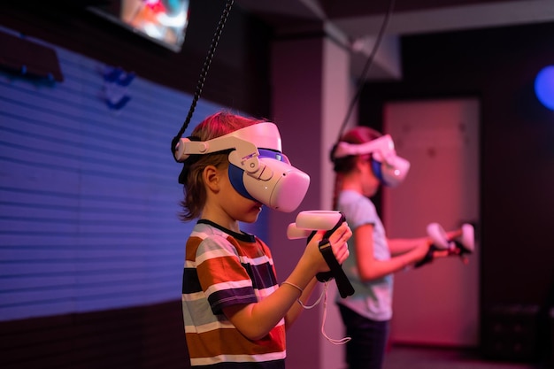 Jogo vr e equipe de realidade virtual crianças amigos jogadores divertidos jogando no videogame de simulação futurista em óculos 3d e joysticks na sala vr de entretenimento com tecnologia de inovação e luz neon