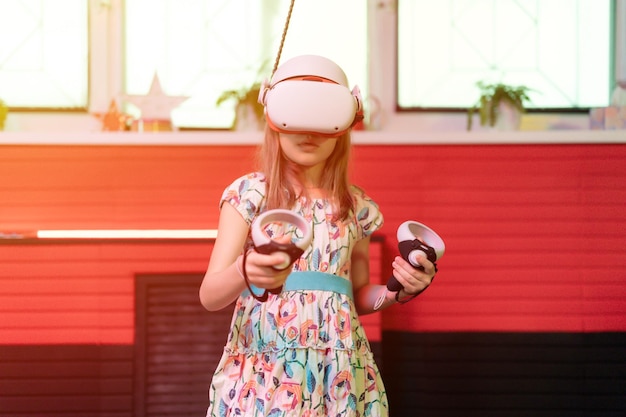 Jogo vr e realidade virtual garoto menina gamer diversão de oito anos jogando na filmagem de simulação futurista ou explore o jogo de estudo em óculos 3d e joysticks no alargamento da tecnologia da sala vr