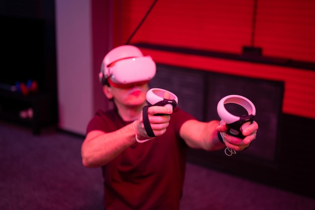 Jogo vr e realidade virtual homem gamer divertido jogando no jogo de tiro de simulação futurista em óculos 3d e joysticks arma na sala vr de entretenimento com tecnologia de inovação e luz neon