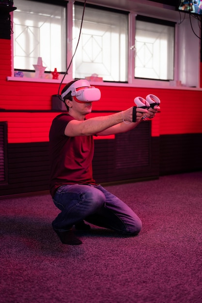 Jogo vr e realidade virtual homem gamer divertido jogando no jogo de tiro de simulação futurista segurando nas mãos joysticks arma na sala vr de entretenimento com tecnologia de inovação e luz neon