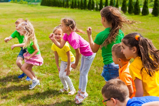 Jogos ativos para crianças em idade escolar e pré-escolares no ar. agachar  e pular. jogo ao ar livre para grupo de crianças.