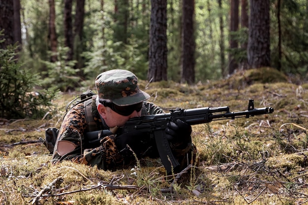 Jogos de equipes de guerra adultos com armas, airsoft ou bola de ataque, na floresta. soldado do exército em uniforme de camuflagem militar com óculos, arma nas mãos. soldado de meia-idade com uniforme da floresta e autogun