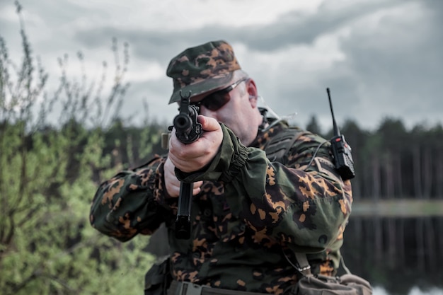 Jogos de equipes de guerra adultos com armas, airsoft ou bola de ataque, na floresta. soldado do exército em uniforme de camuflagem militar com óculos, arma nas mãos. soldado de meia-idade com uniforme da floresta e autogun