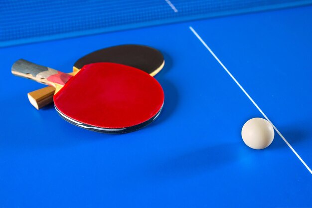 Foto jogos de esporte em raquetes de pingue-pongue para tênis de mesa e uma bola na mesa azul