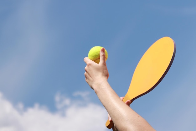 Jogue paddleball com uma raquete de madeira contra um céu azul Tênis de praia Jogos ao ar livre Closeup