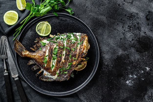 John dory peixe grelhado com limão e salsa em uma panela.