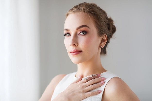 joias, luxo, casamento e conceito de pessoas - mulher sorridente em vestido branco com brinco de diamante e anel