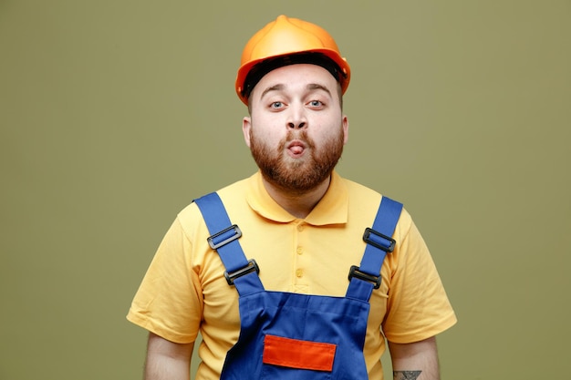 Jokin mirando a la cámara joven constructor hombre en uniforme aislado sobre fondo verde