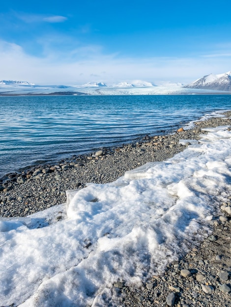 Foto jokulsarlon-eisberglagune mit gletscher und großem eisberg unter bewölktem blauem himmel in island