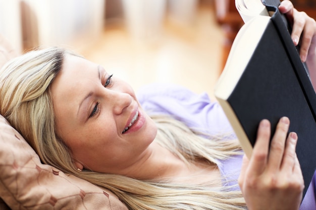 Jolly mulher lendo um livro deitado em um sofá