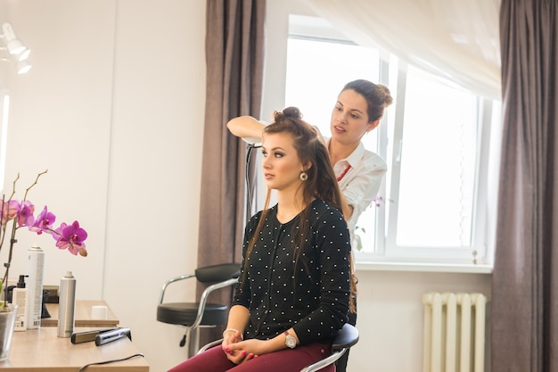 Jornada laboral dentro del salón de belleza. El peluquero hace el peinado del cabello.