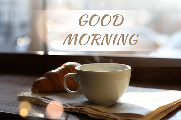 Foto jornal de café delicioso good morning e croissant perto da janela dentro de casa