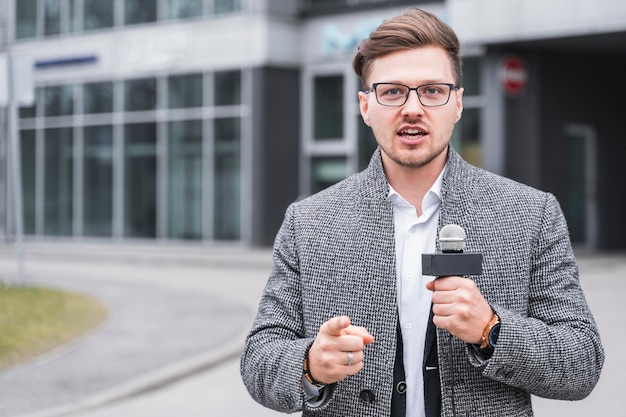 Jornalista masculino de alto ângulo apontando