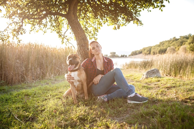 Jouful junge Mädchen streicheln ihren Hund in Sportkleidung und genießen ihre Zeit und ihren Urlaub im sonnigen Park