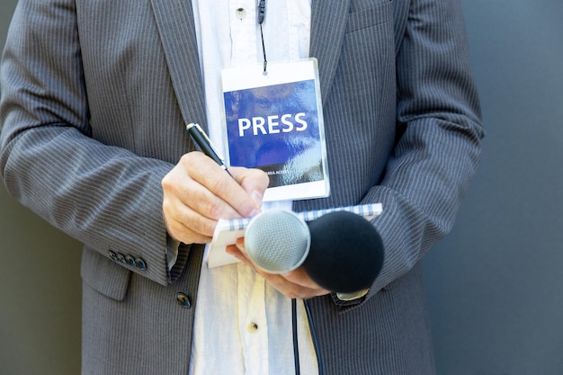 Journalist bei einer Medienveranstaltung oder Pressekonferenz mit einem Mikrofon und Notizen