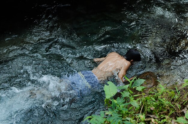 Foto jovem a nadar na margem profunda do rio