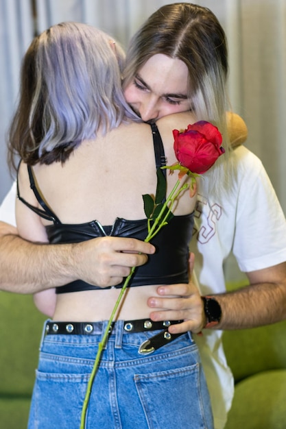 Jovem abraçando namorada agradecendo por presente romântico surpresa jovem feliz e atraente segurando um casal de rosas comemorando aniversário de aniversário ou dia dos namorados