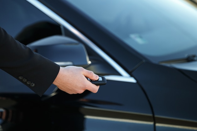 Jovem, abrindo a porta do carro com a chave remota de controle