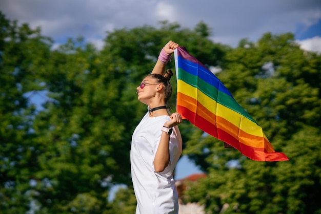 Jovem acenando a bandeira do orgulho LGBT no parque