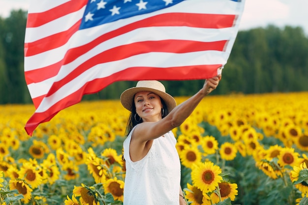 Jovem acenando com a bandeira americana no campo de girassol 4 de julho conceito do Dia da Independência dos EUA