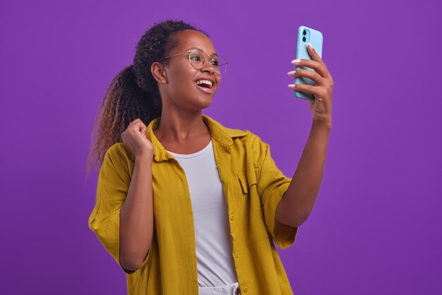 Jovem admirando a mulher afro-americana com telefone faz mão acenando triunfante