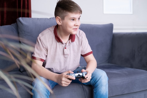 Foto jovem adolescente animado jogando videogame com joystick sentado no sofá em casa