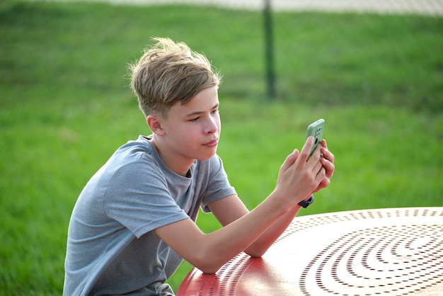 Jovem adolescente bonito usando smartphone ao ar livre no dia ensolarado de verão Conceito de geração de tecnologia